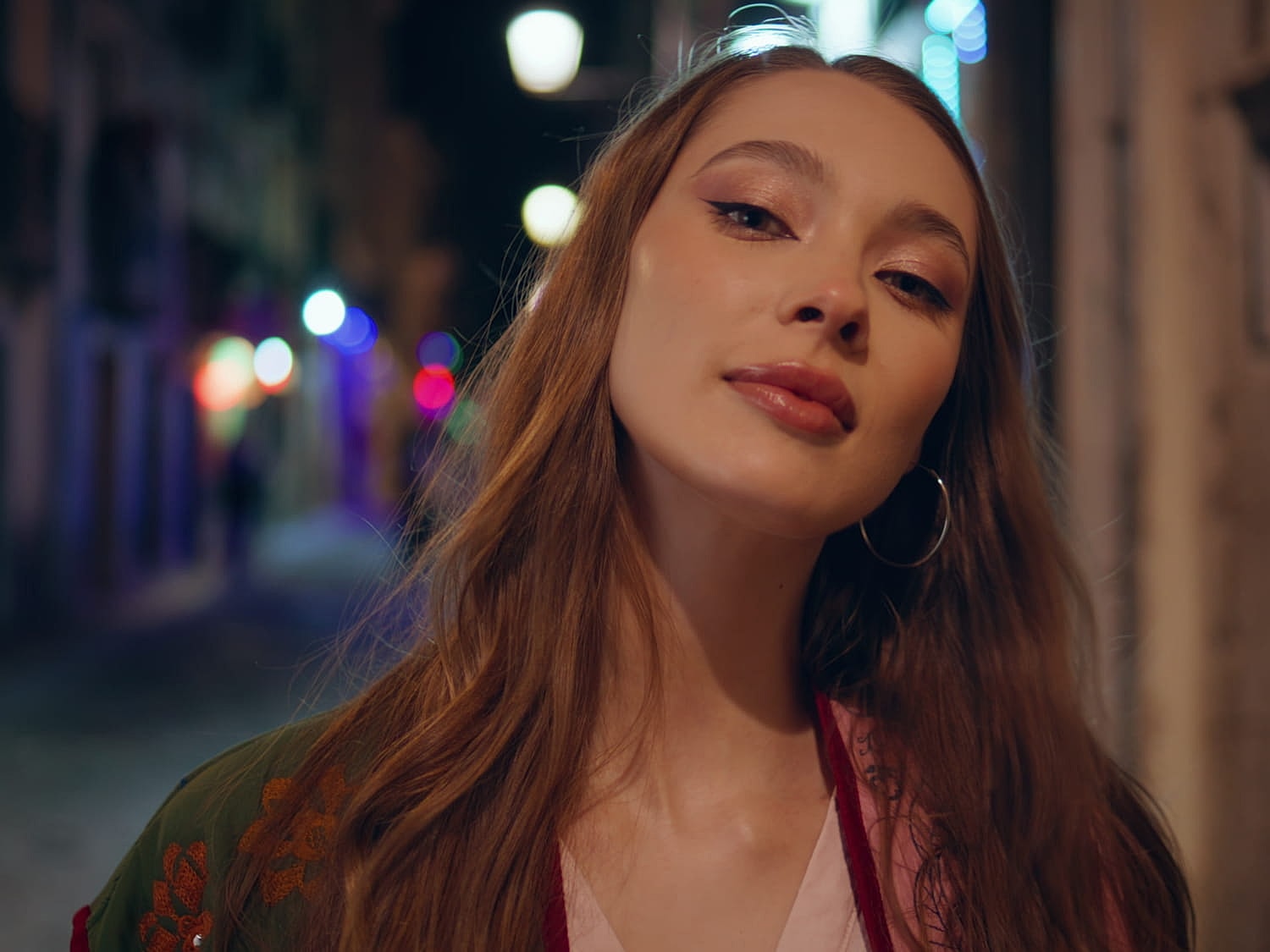 Woman posing in a vibrant, illuminated alleyway.