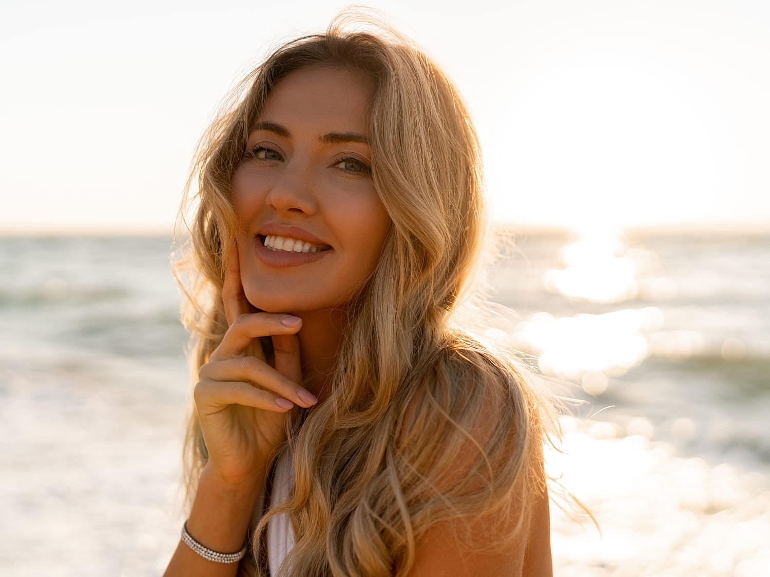 Woman smiling by the beach at sunset.