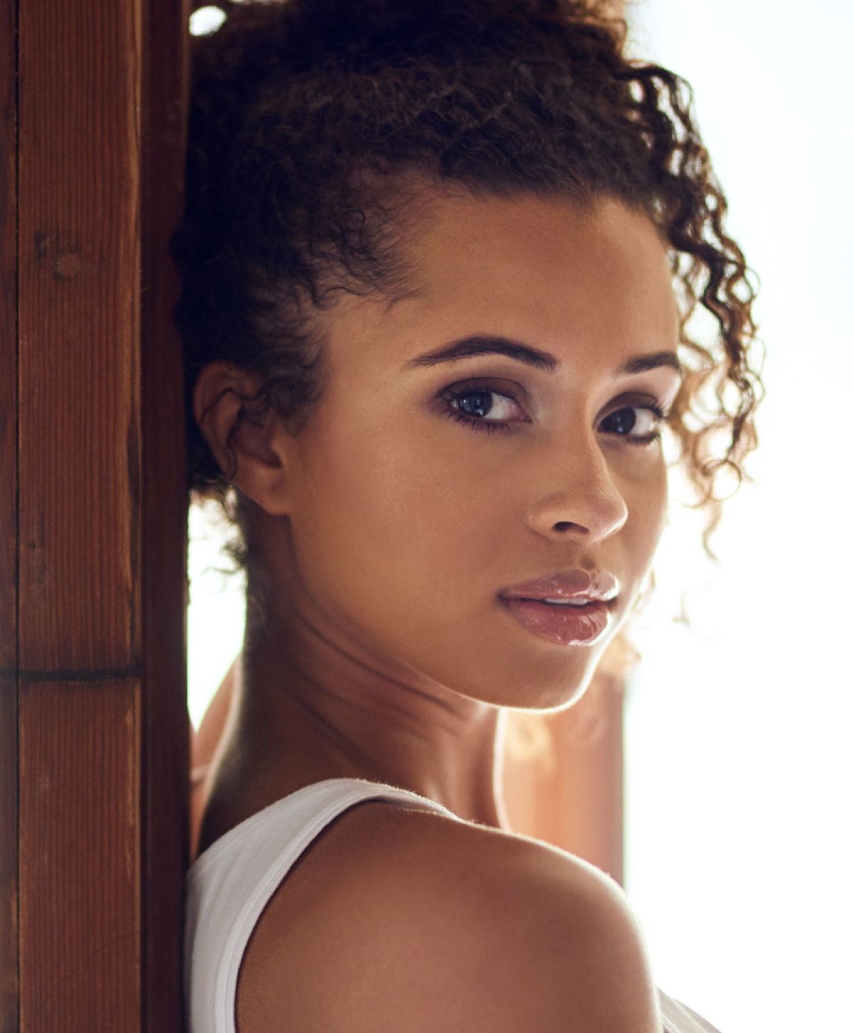 Woman with curly hair leaning against a wall.