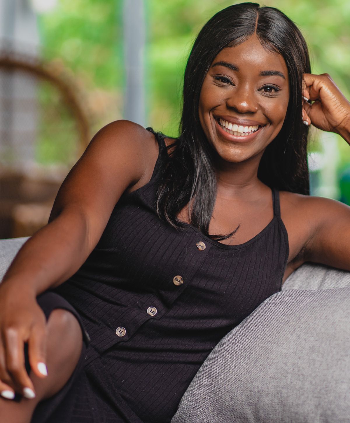 Smiling woman in black dress, relaxing indoors.
